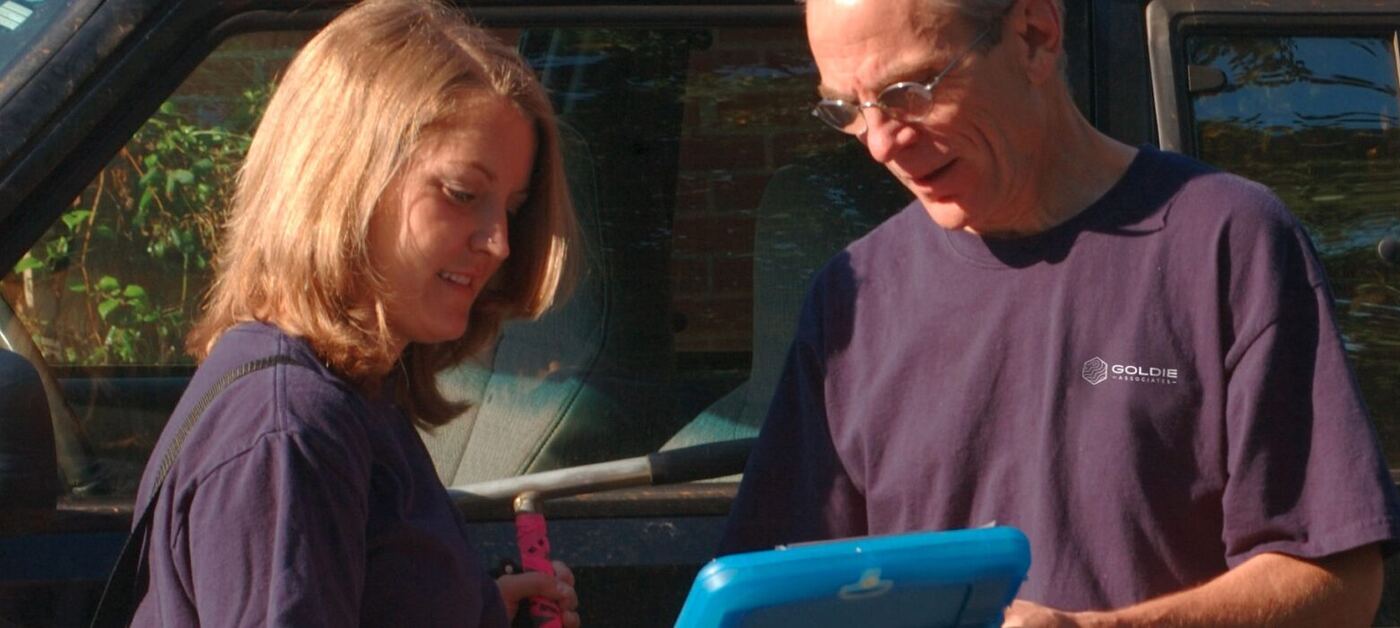 Two Goldie Associates team members reviewing field notes beside a company truck