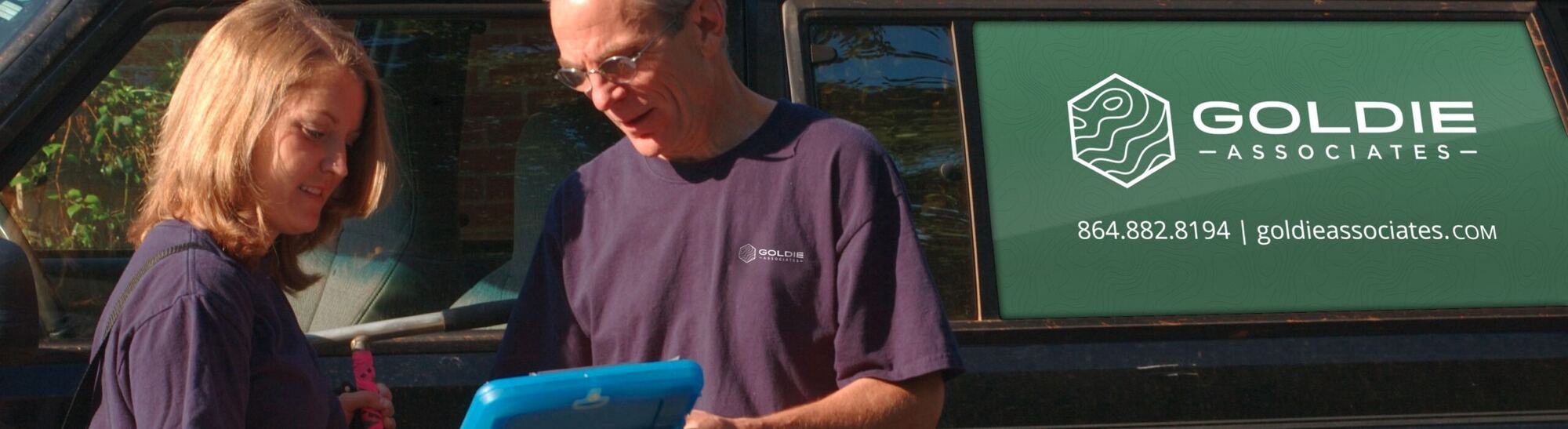 Goldie Associates team members in the field with a company truck